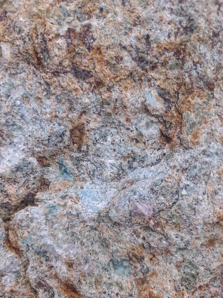 Rough natural stone texture with a mix of gray, violet, and earthy tones, perfect for backgrounds, construction, or design elements photo