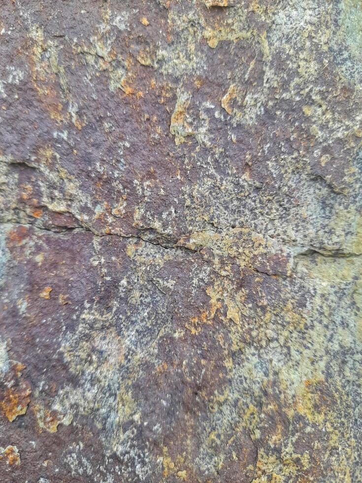 Rough natural stone texture with a mix of gray, violet, and earthy tones, perfect for background or design elements. photo