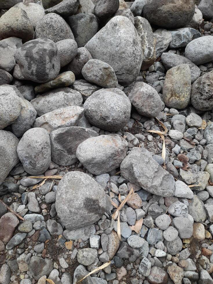 A close up image of variously sized and colored river stones, showcasing natural textures and earthy tones in a tightly packed arrangement photo