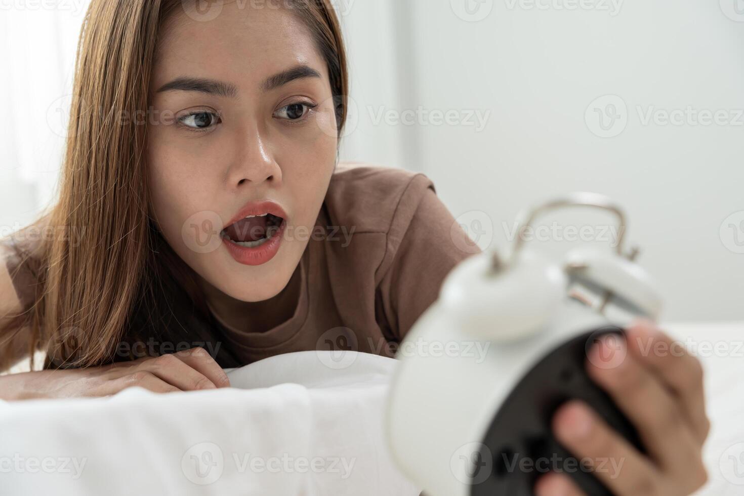 Shocked Asia young woman looking at clock alarm, lady is late appointment or work or class study, overslept, difficulty get up in mornings, time worried, not on time, sleepy, photo