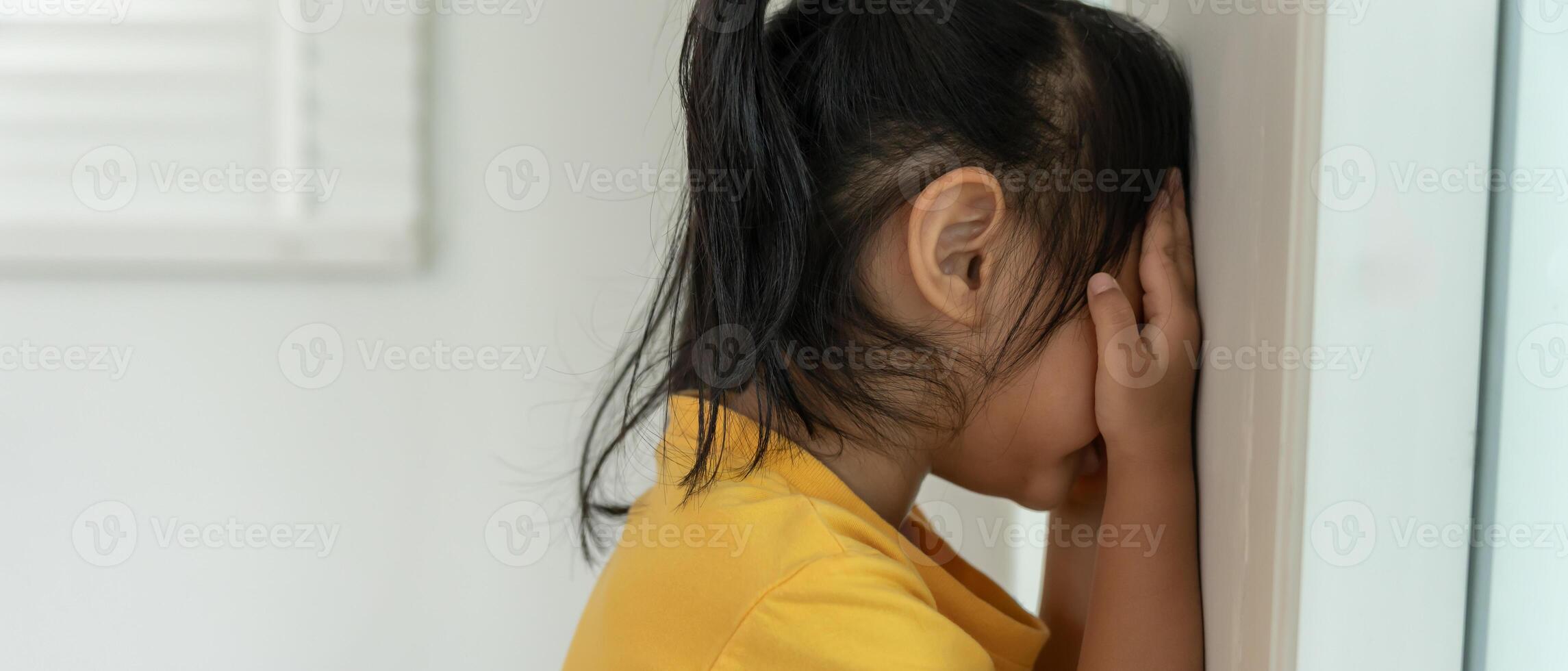 little asian children girl covering his eyes with hands, playing hide and seek standing next a wall house, Adorable child having fun in the home. happy family have fun with kids, activity photo