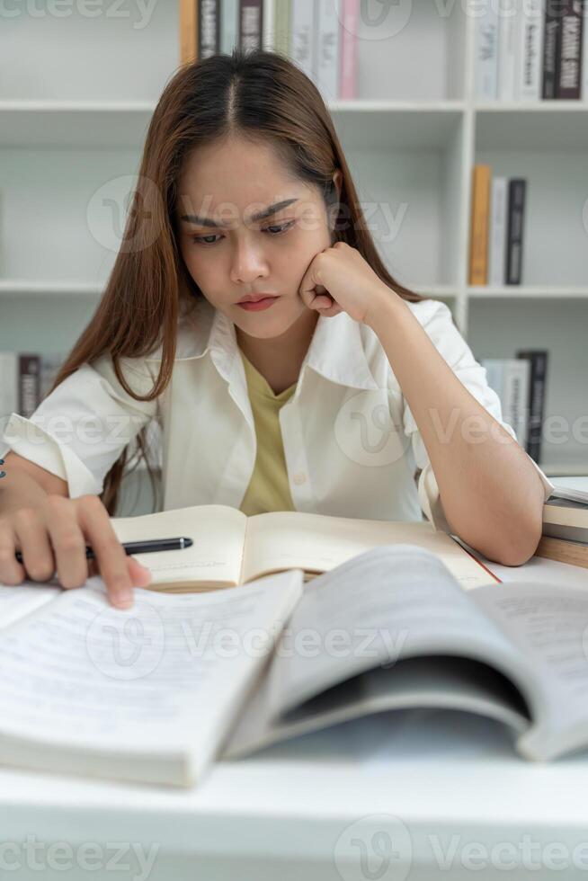 Asian student woman have anxiety because of exams, female prepare for test and learning lessons in the library. stress, despair, haste, misunderstanding reading,, expectation, knowledge photo