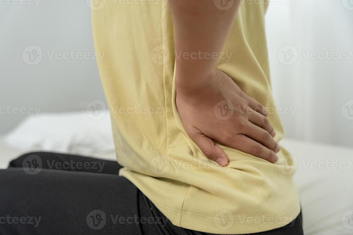 holding lower back while and suffer from unbearable pain health and problems, chronic back pain, backache in office syndrome, scoliosis, herniated disc, muscle inflammation photo