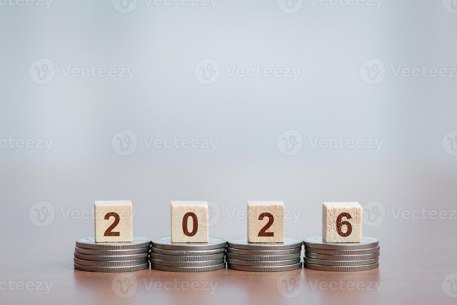 Stacked coins form a foundation for wooden blocks displaying '2026,' concept of financial growth or planning for the future. photo