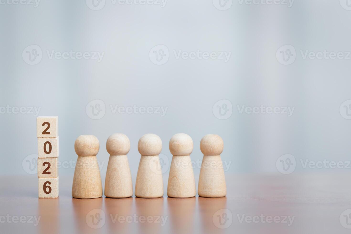 Five wooden figurines stand in a row beside stacked blocks displaying '2026,' concept of planning and the future. photo