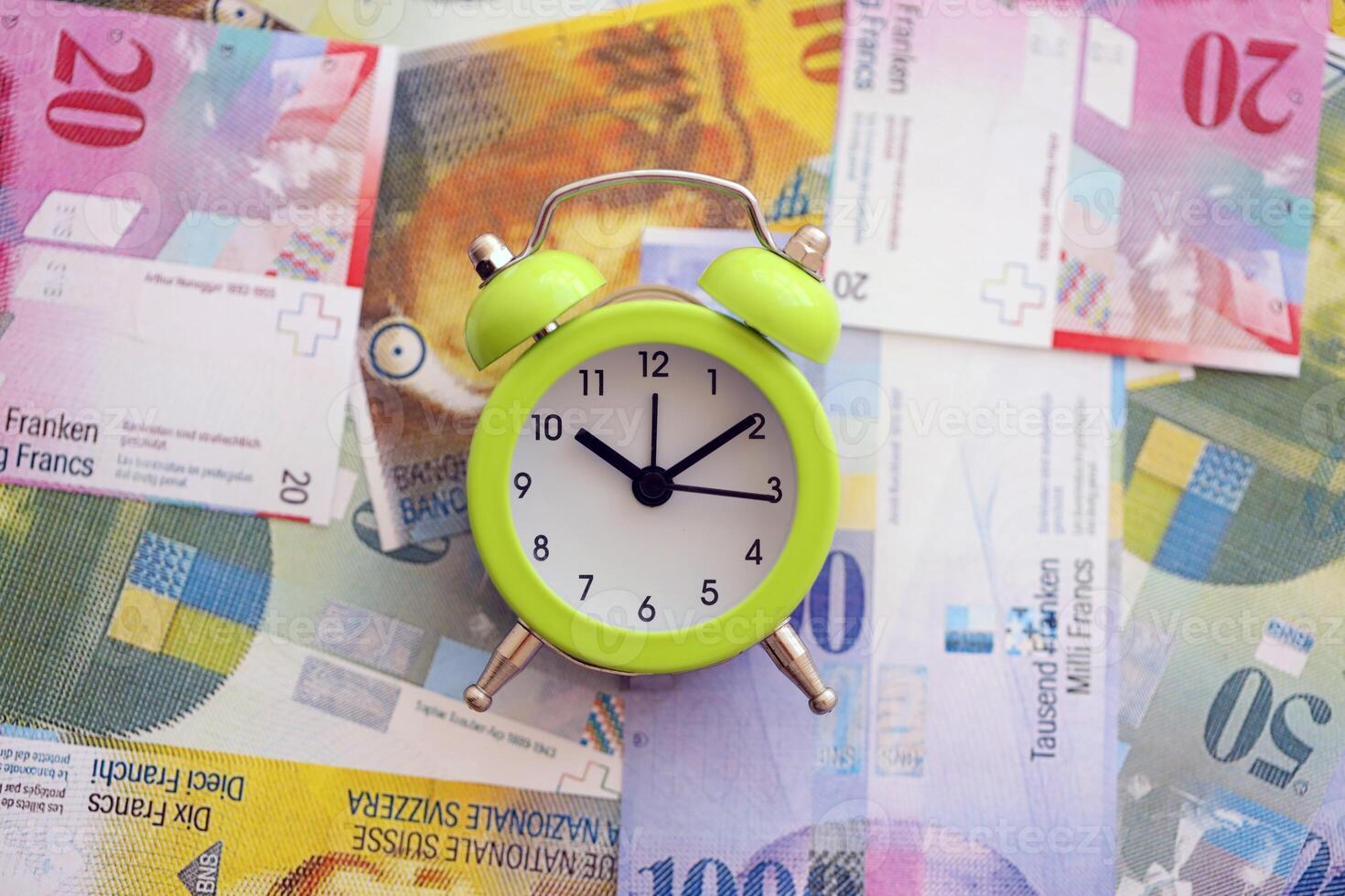 Swiss franc banknotes and alarm clock. The current francs money bills and clock lies on table photo