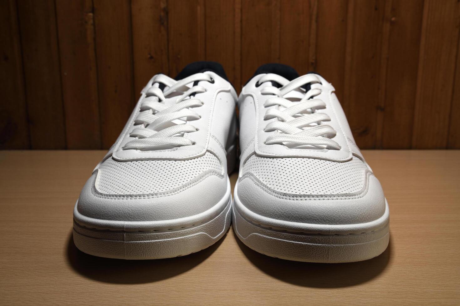 Front view extreme macro photography of brand new white sneakers on yellow wooden shelf photo