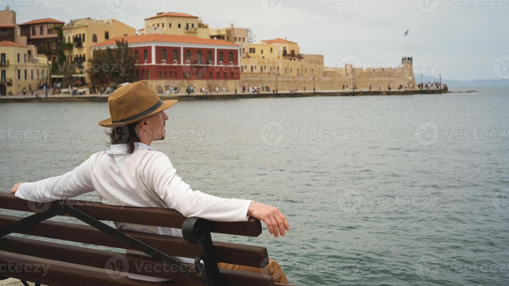 Tourist relaxing on bench enjoying view of chania, crete, greece photo