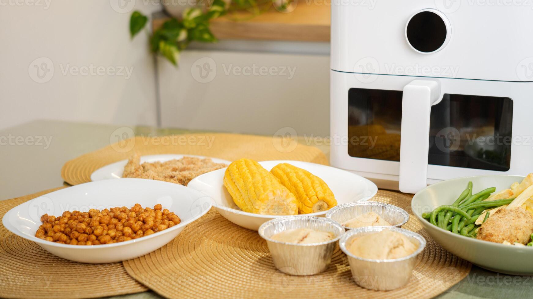 Air fryer cooking various dishes including corn, muffins, and vegetables photo