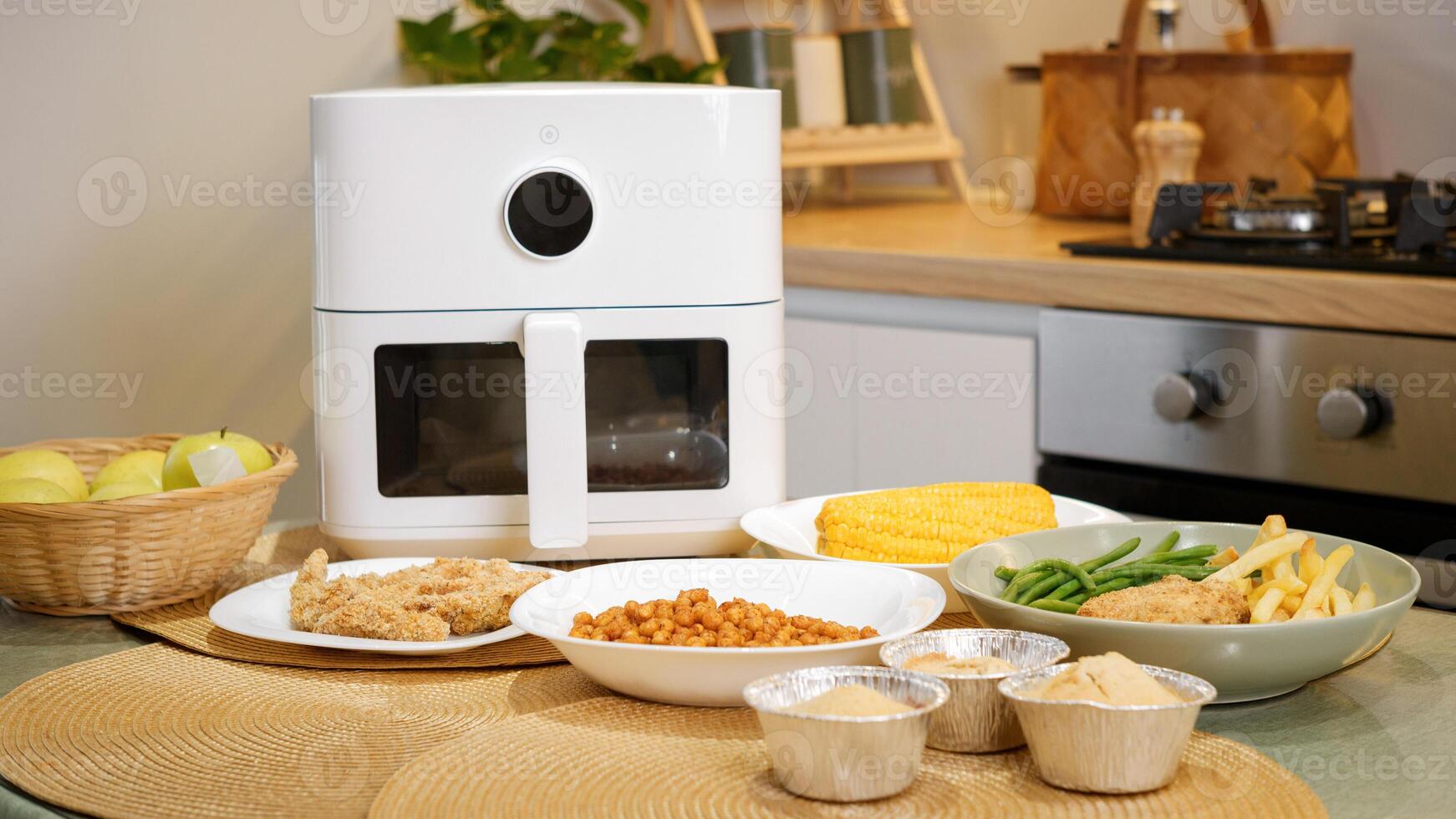 Modern air fryer cooking various dishes in kitchen. chicken, vegetables, and more photo