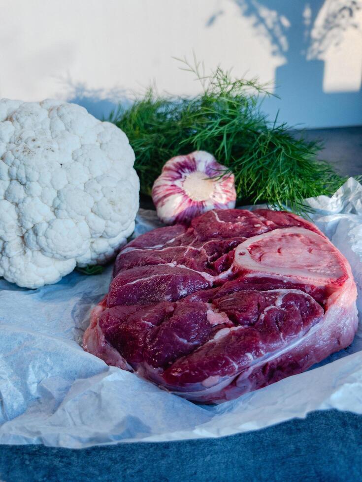 Beef Shank with Bone and Fresh Vegetables on Parchment Paper photo