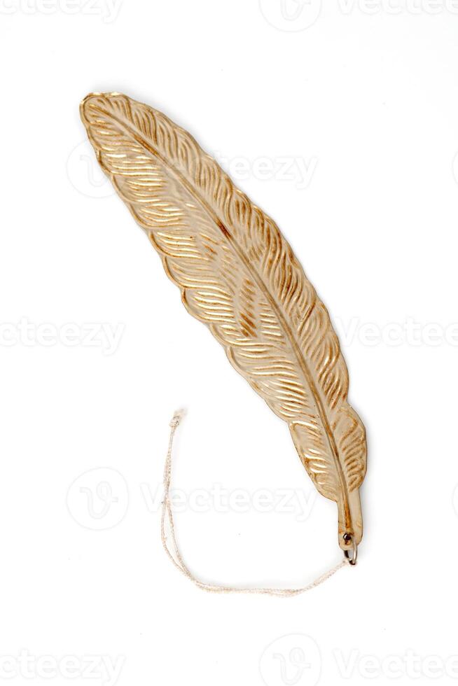 Golden feather-shaped ornament with string, isolated on white background. Elegant decorative object for interior design. photo