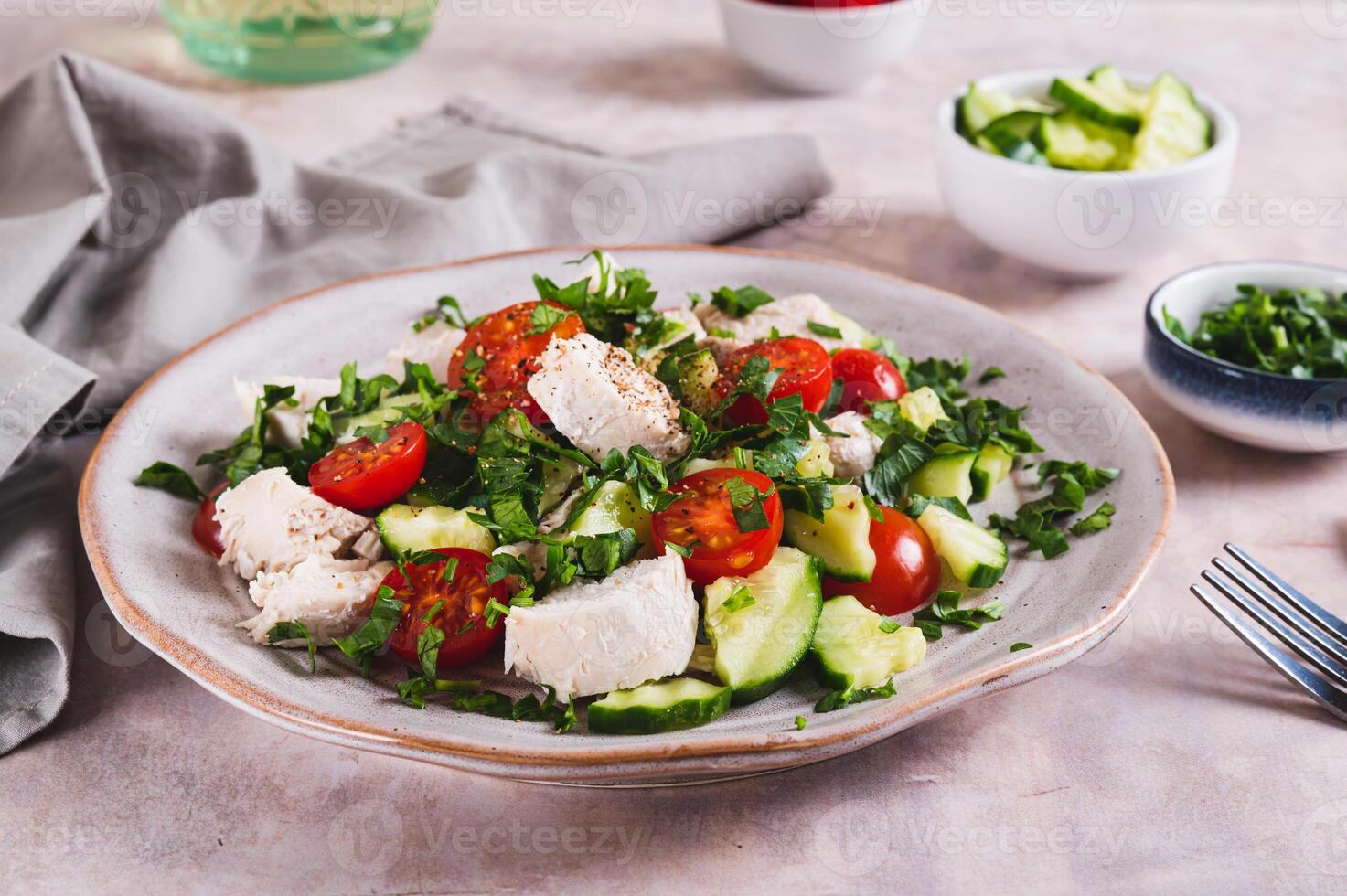Homemade salad with cucumber, tomatoes, chicken and herbs on a plate on the table photo