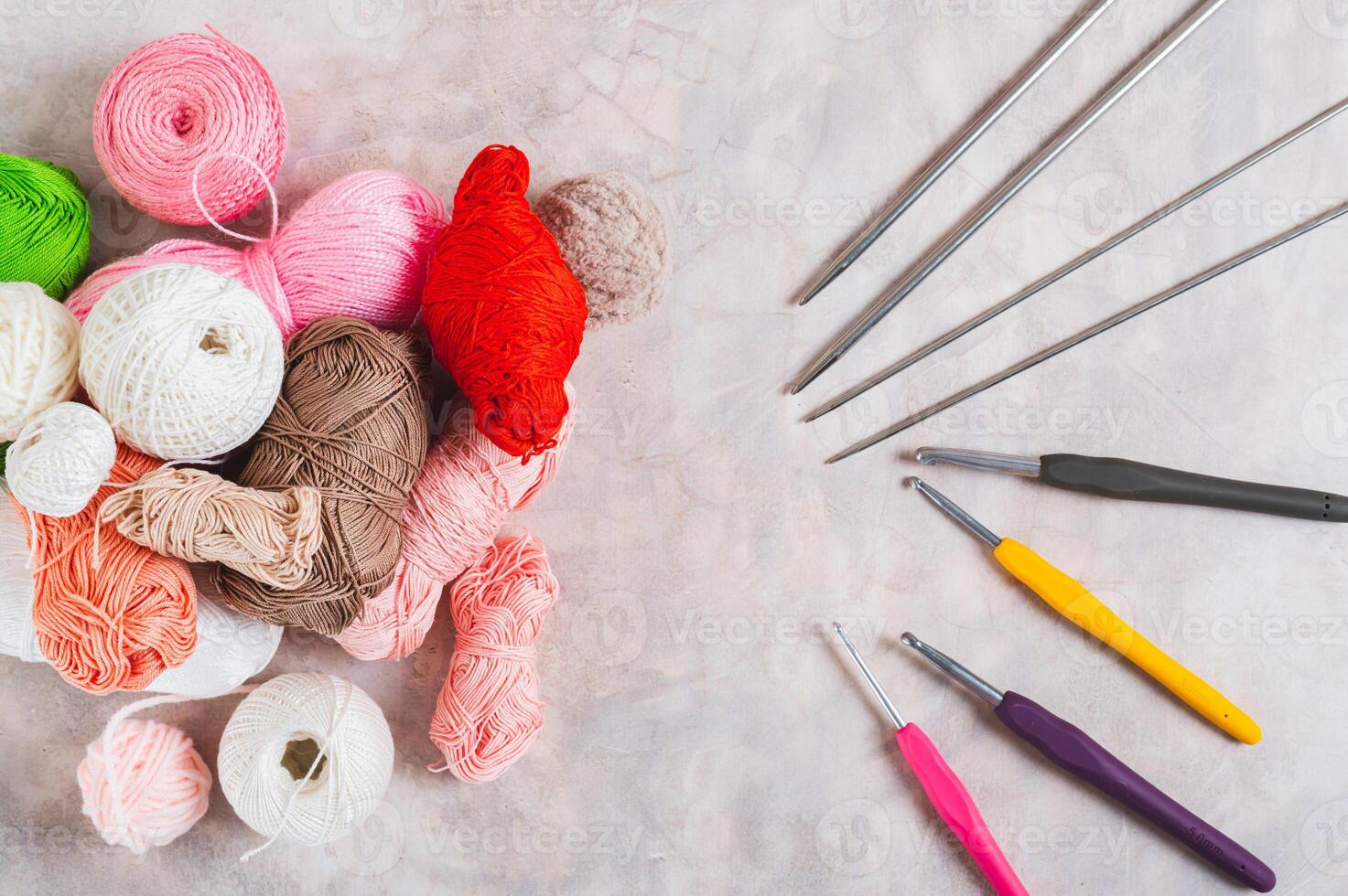 Lots of colorful skeins of yarn, crochet hooks and knitting needles on a table top view photo