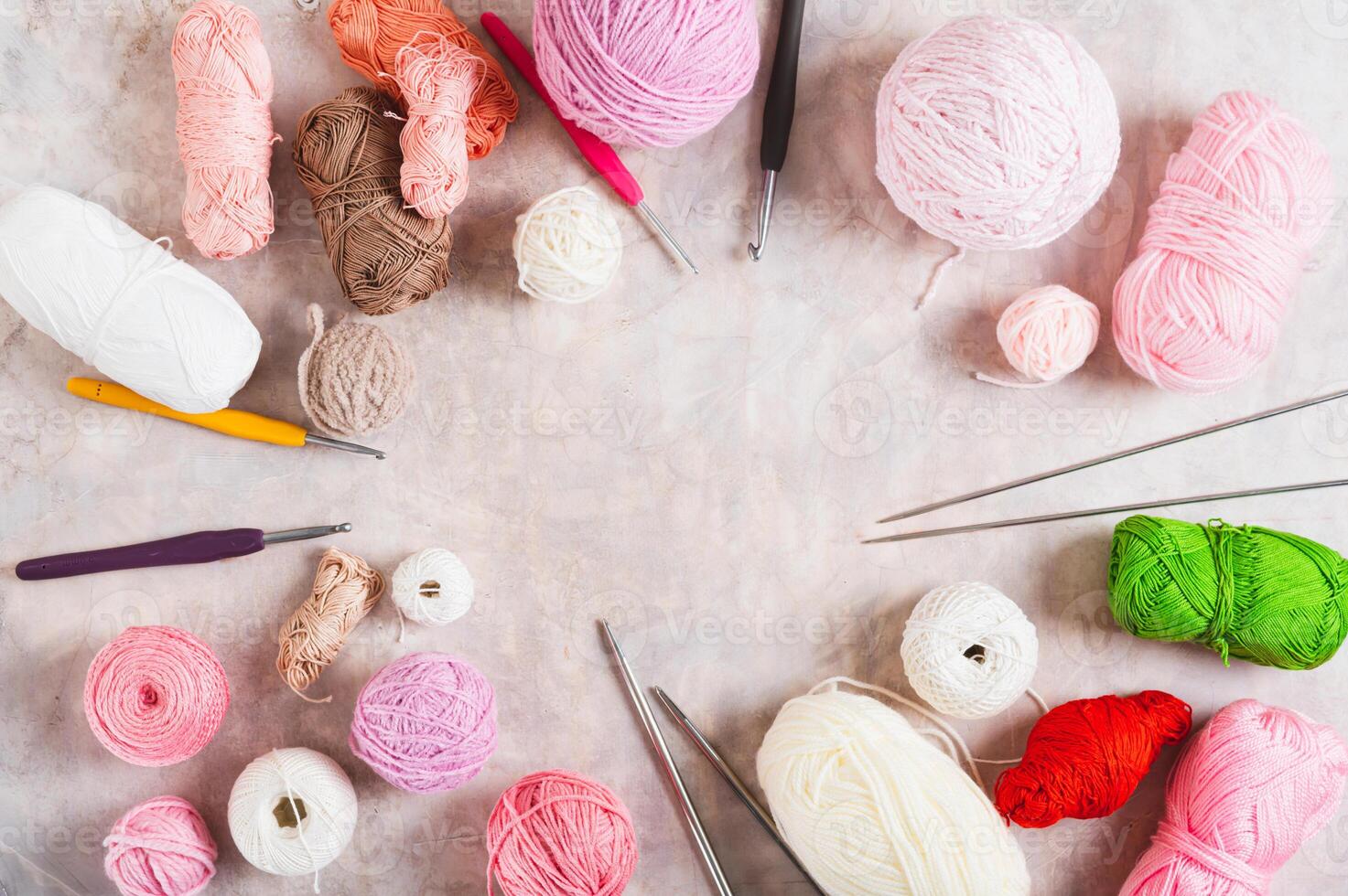 Frame of colored balls of wool and cotton, hooks and knitting needles on the table top view photo