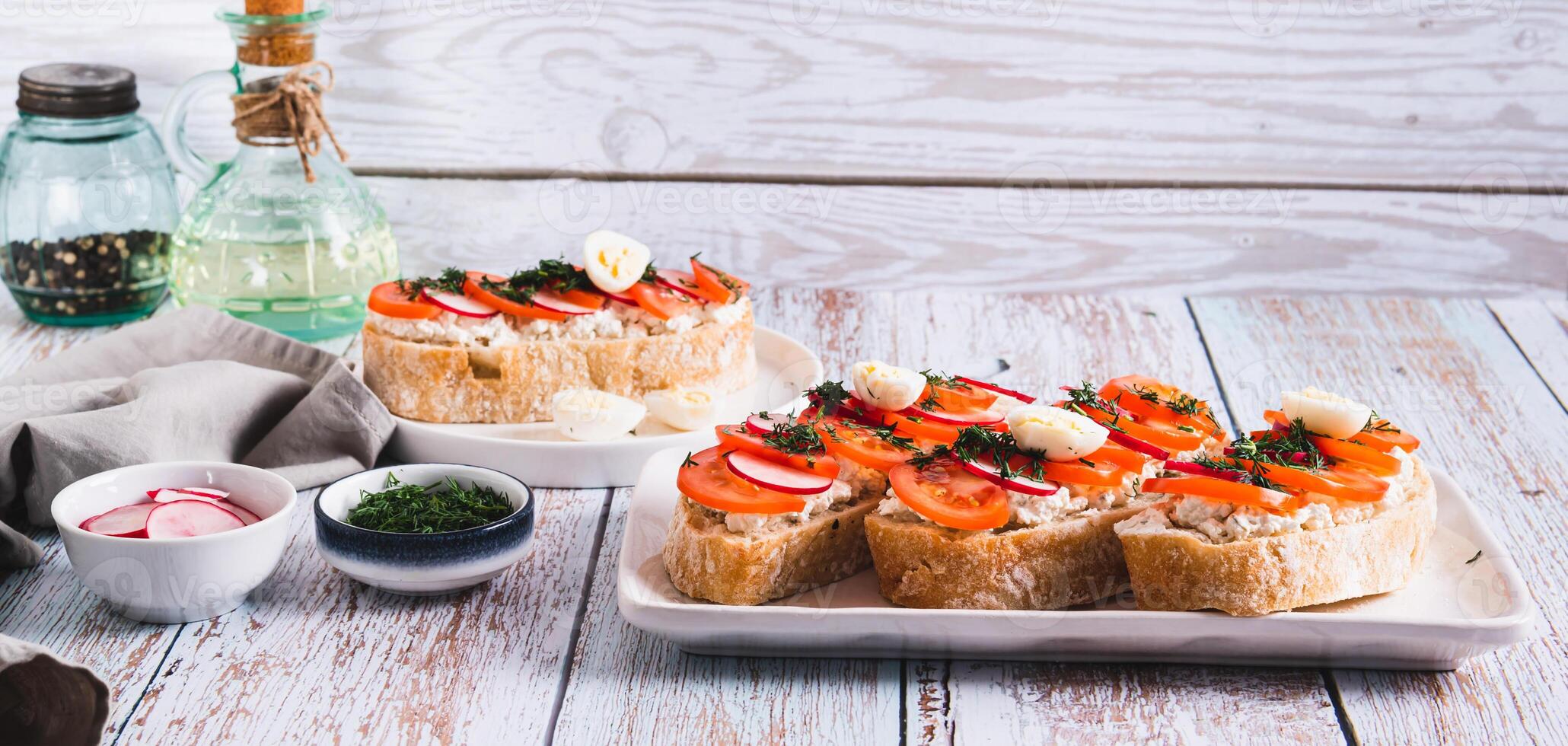 Appetizing bruschetta with ricotta, tomato, radish and quail egg on a plate web banner photo