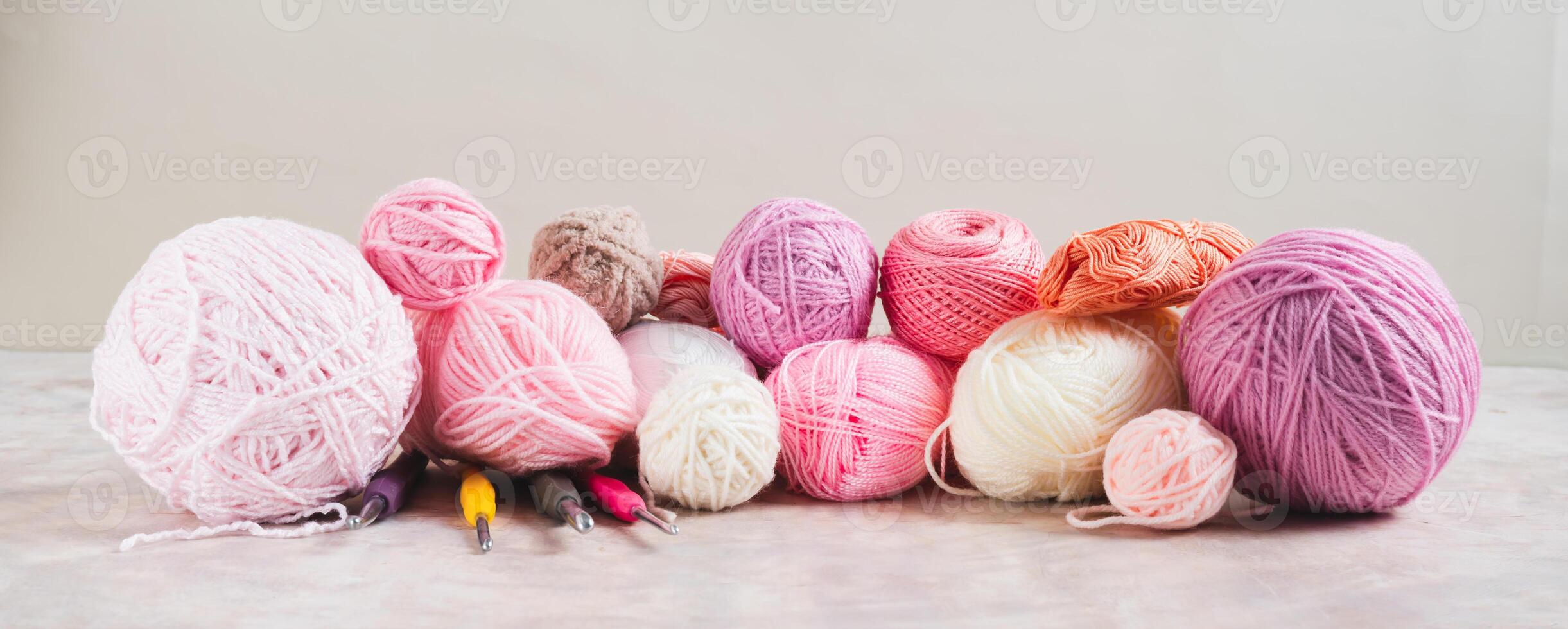 Lots of colorful skeins of yarn, crochet hooks and knitting needles on a table web banner photo