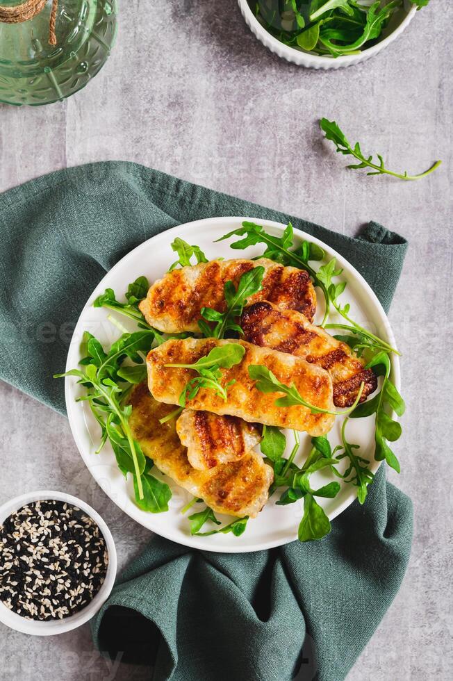 Crispy fried halloumi cheese and arugula leaves on a plate on a table top and vertical view photo