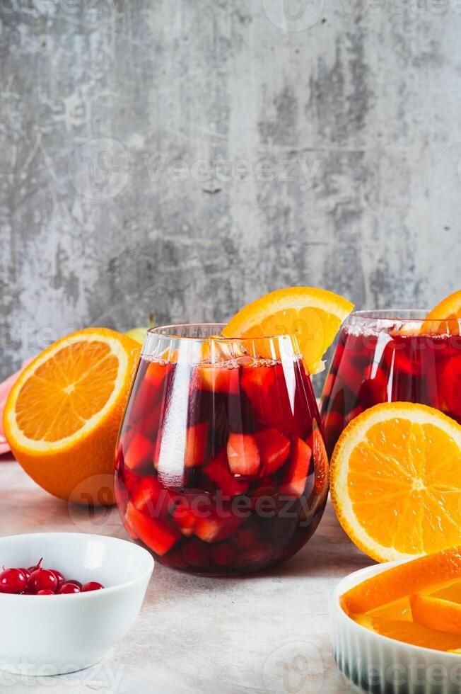 Refreshing summer sangria cocktail with fruits and berries in glasses on the table vertical view photo