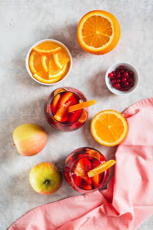 Sangria cocktail with red wine and fruits in glasses on table top and vertical view photo