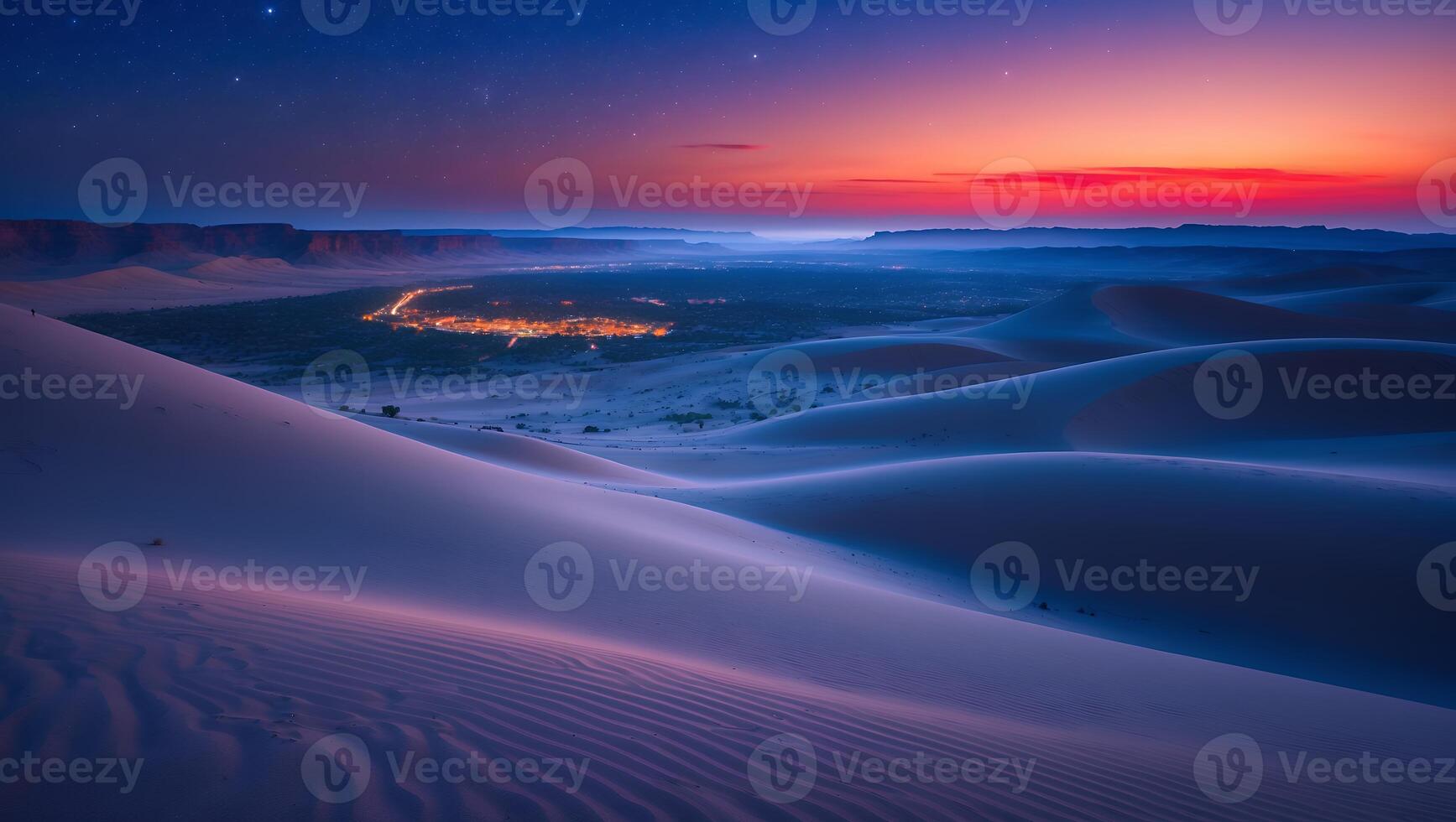 Desert Dunes at Night with Distant City Lights and Colorful Sky photo