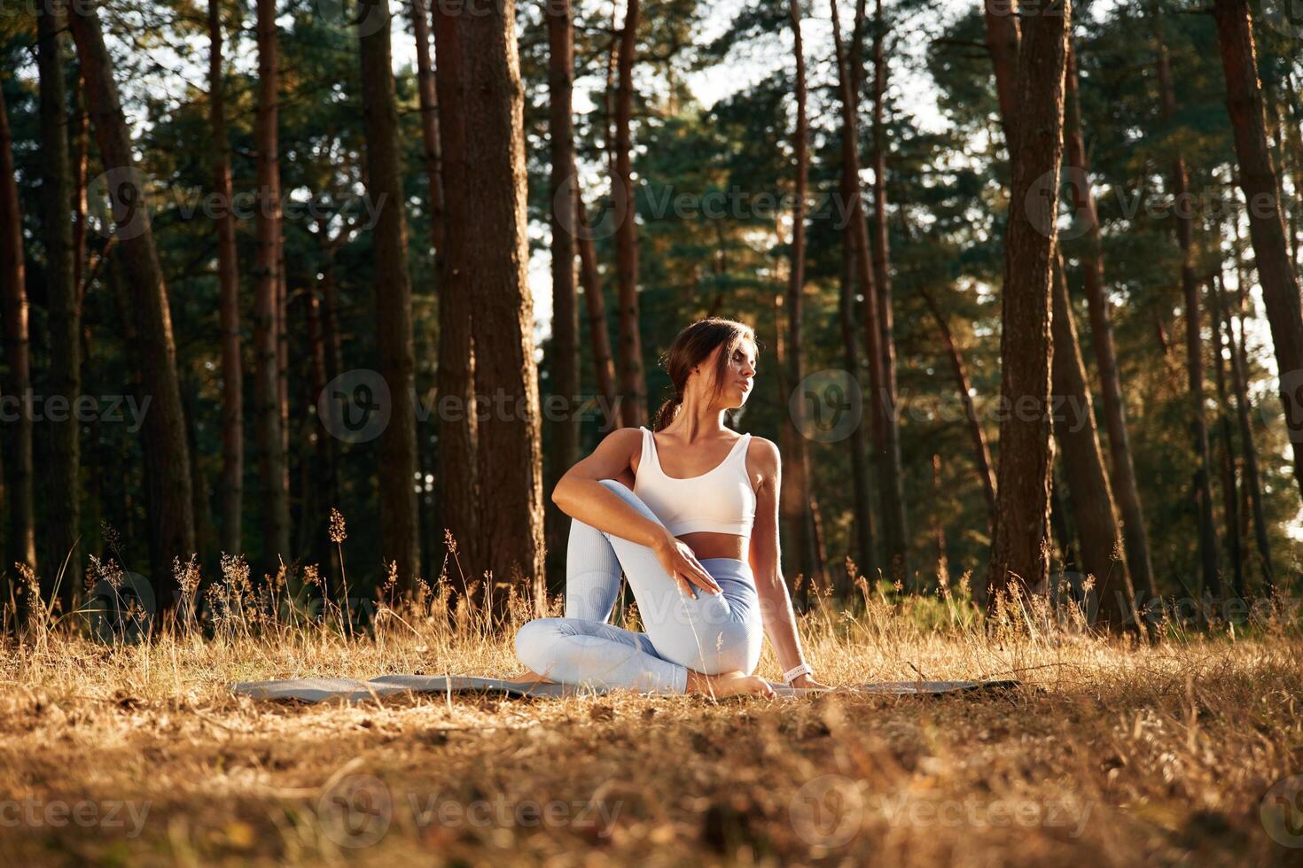 On the mat..,. Woman is doing yoga fitness exercises in the forest photo