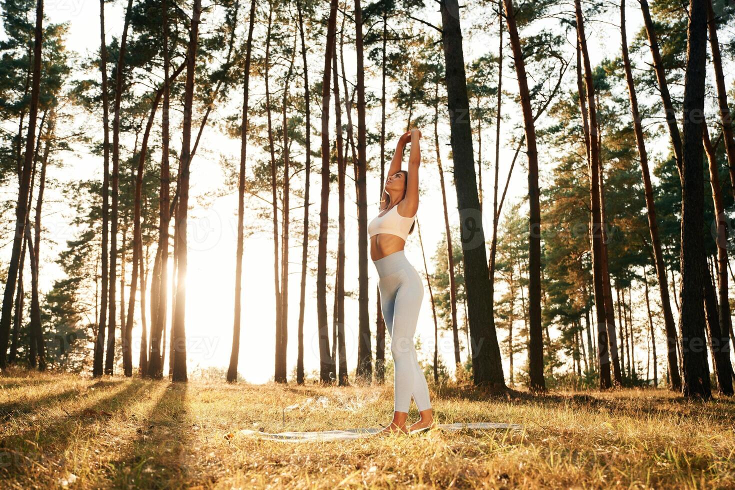 Stretching up,,, warm up exercises. Woman is doing yoga fitness exercises in the forest photo
