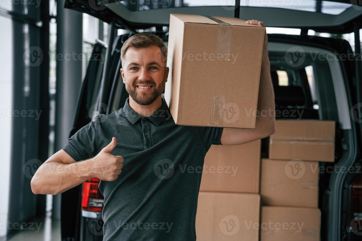 Box is on the shoulder. Delivery man or loader is near the car with, photo