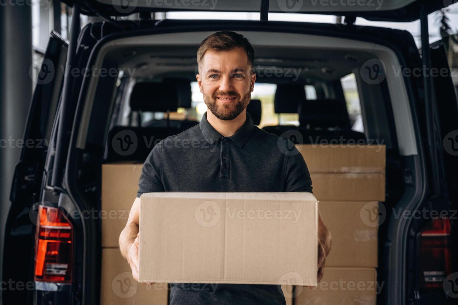 Holding the packed product in hands..., Delivery man or loader is near the car with a box photo