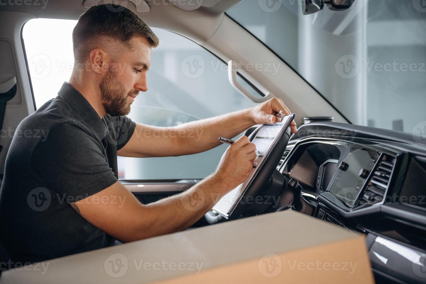 Writing ,in the notepad,,, document. The delivery man or a loader is in the car with box photo