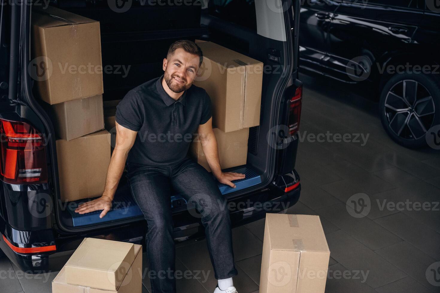 Taking a ,,,break, resting, sitting. Delivery man or loader is near the car with a box photo