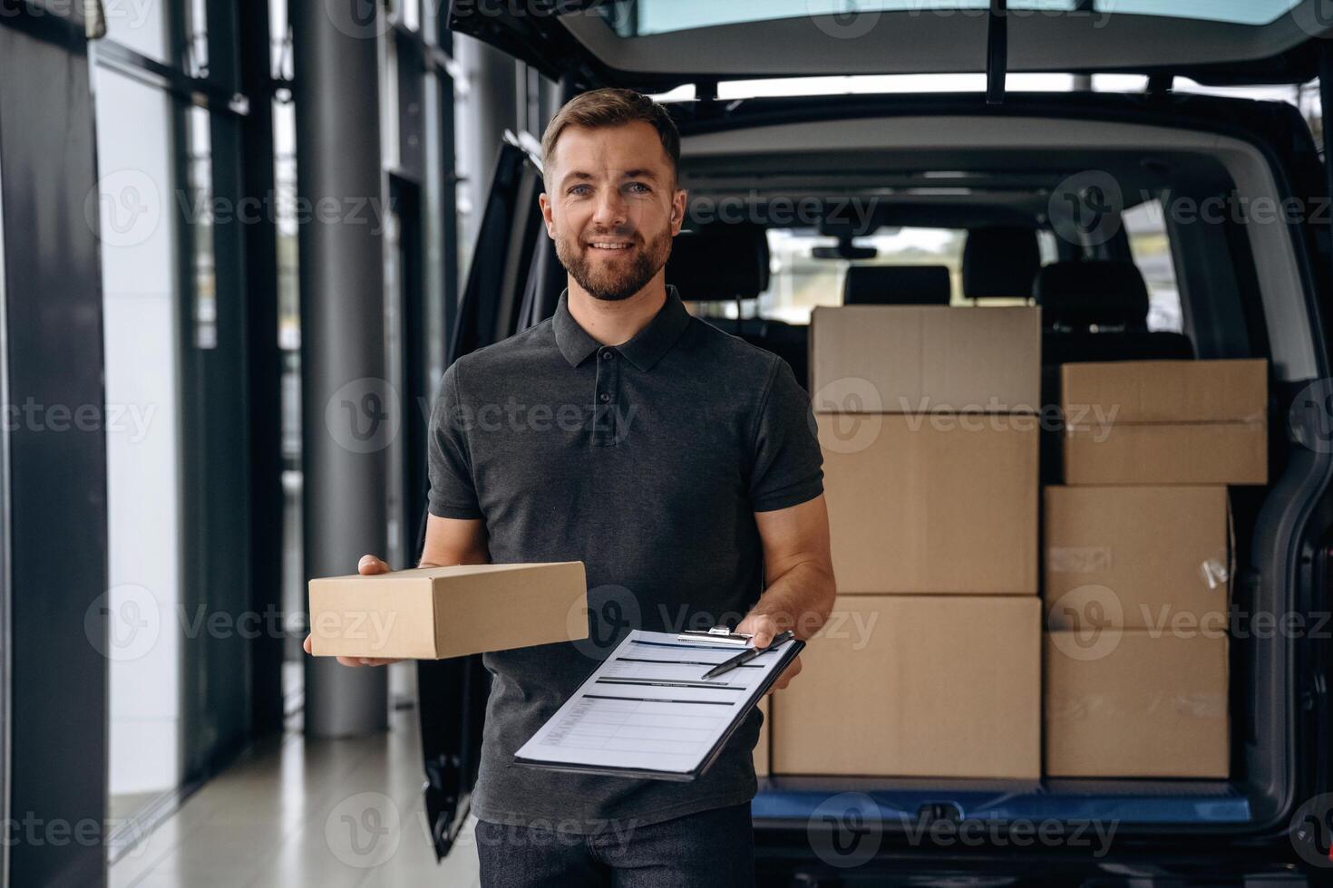 Pen and the notepad ,,in ,hands. Delivery man or loader is near the car with a box photo