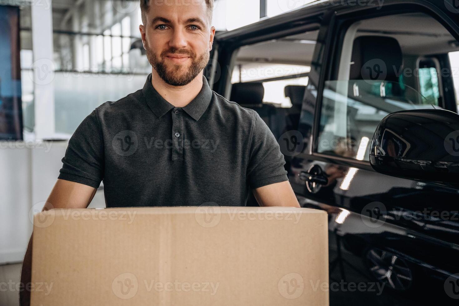 Big,, order, holding ,the ,box. Delivery man or loader is near the car with photo