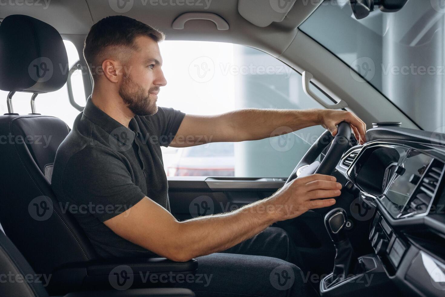 View from, the side. Man, is ,sitting in the car, driver photo