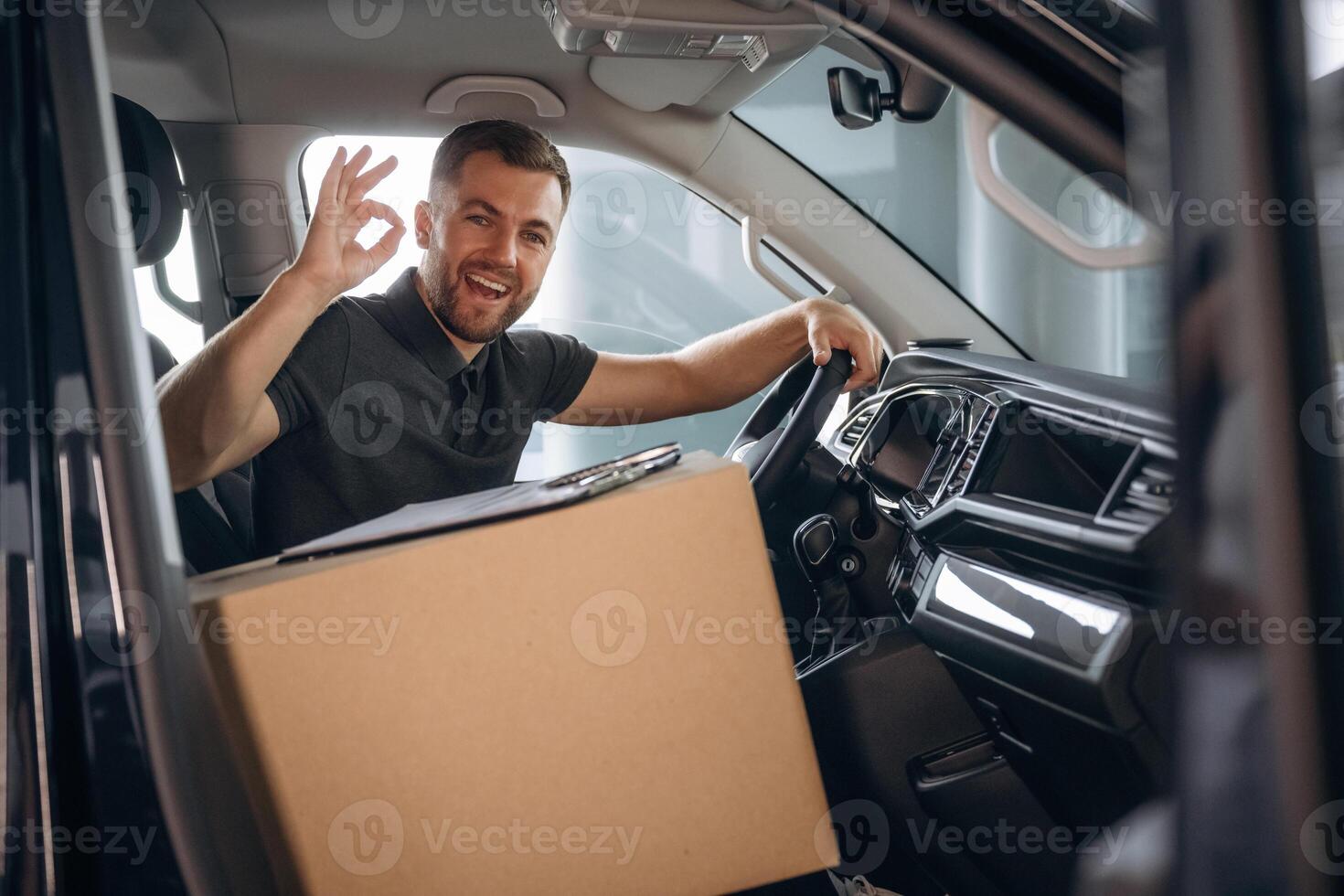Showing, hand gesture, everything is fine, will be done. The delivery man or a loader is in the car with box photo