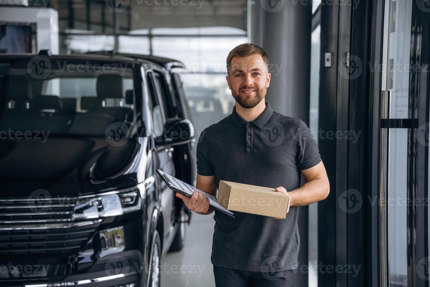 Front view, standing. Delivery,,, man or loader is near the car with a box photo