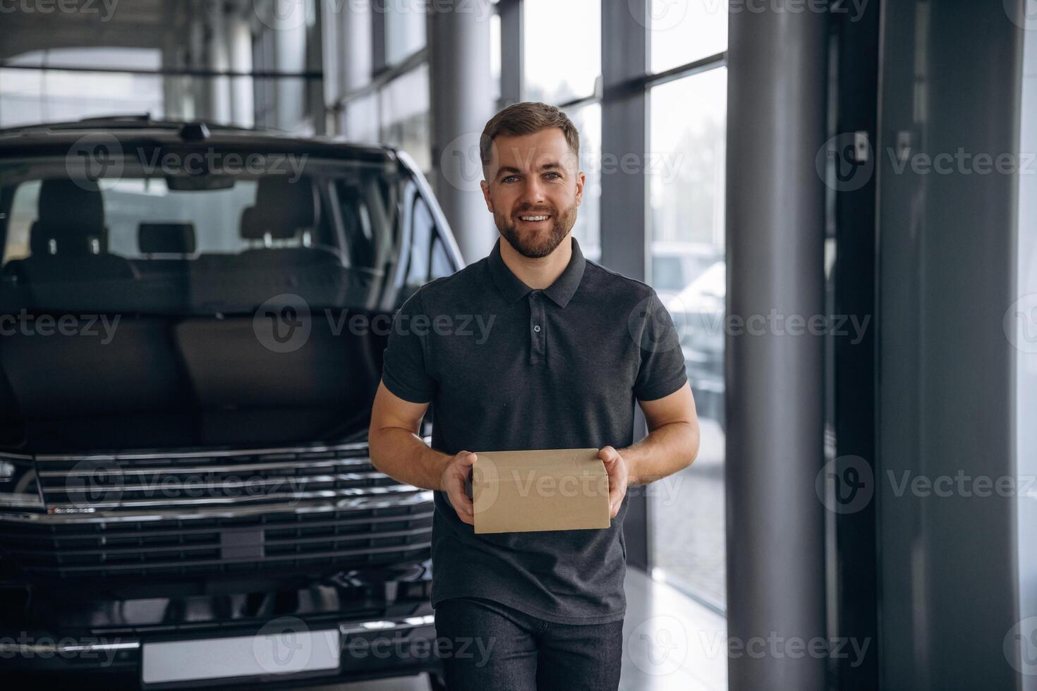 Here's your delivery. Man ,,,loader is near the car with a box photo