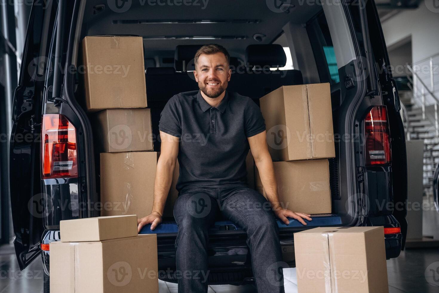 Taking a break,,, resting, sitting. Delivery man or loader is near the car with a box photo