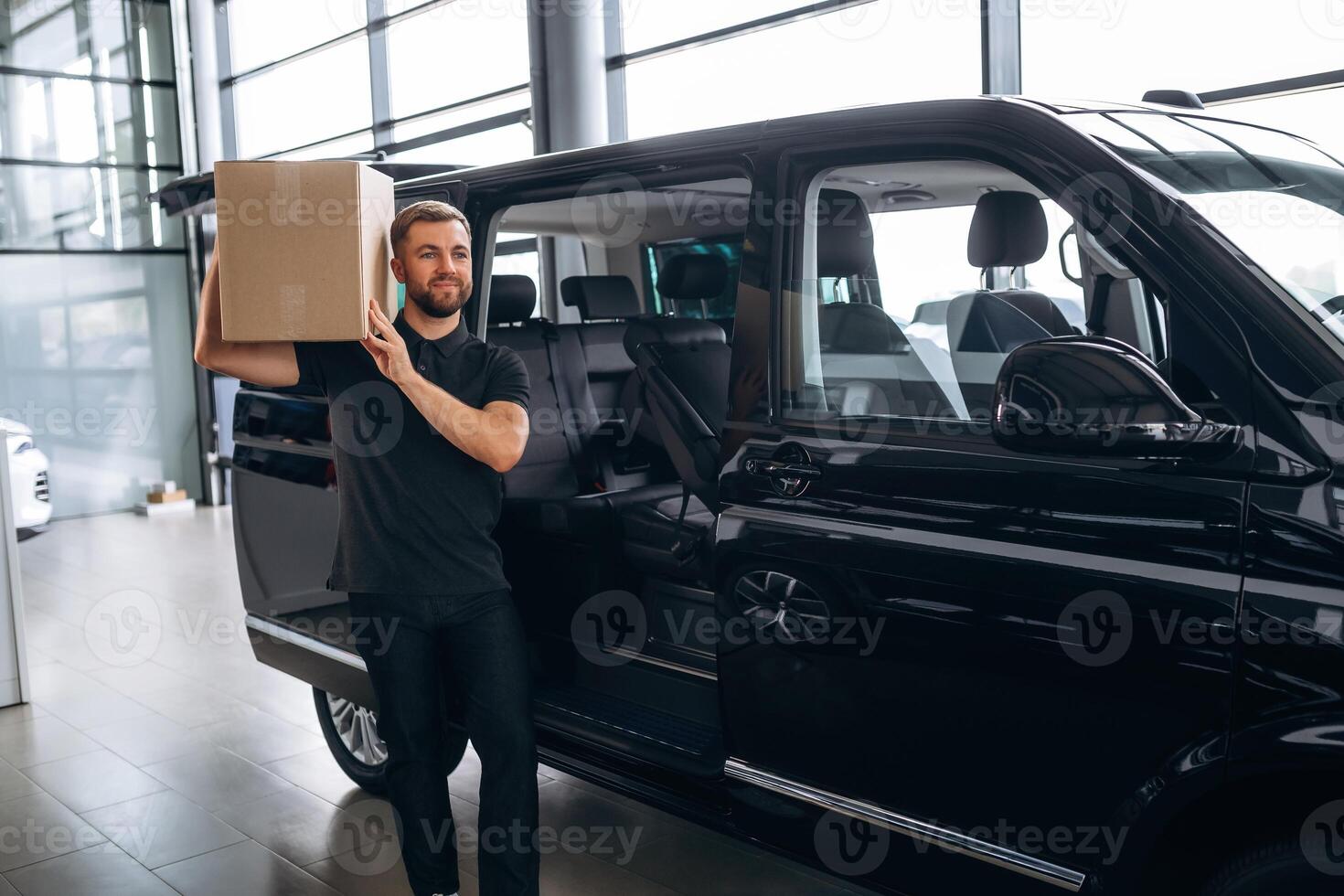 Big ,order, holding ,the box. Delivery man or loader is near the car with photo