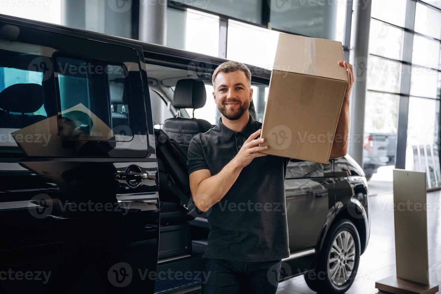 Box is on the shoulder. Delivery man ,or loader is near the car with photo