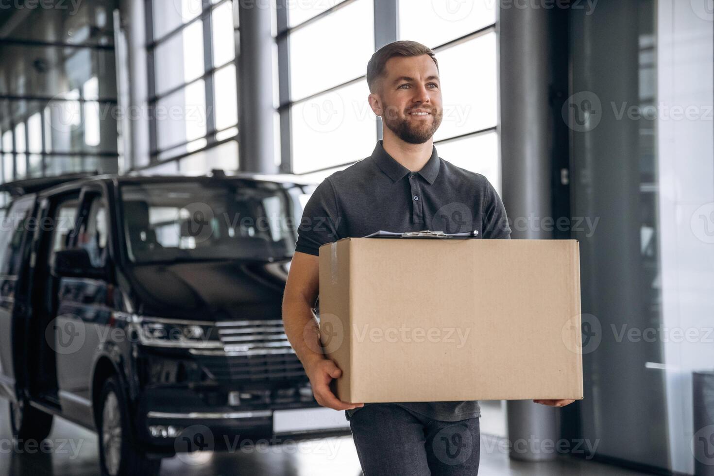 With, a ,box,, smiling. Delivery man or loader is near the car photo