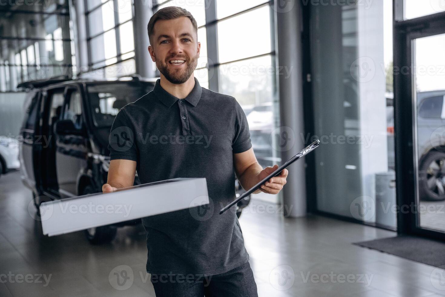 Business of delivery, ,,with notepad. Man loader is near the car with a box photo