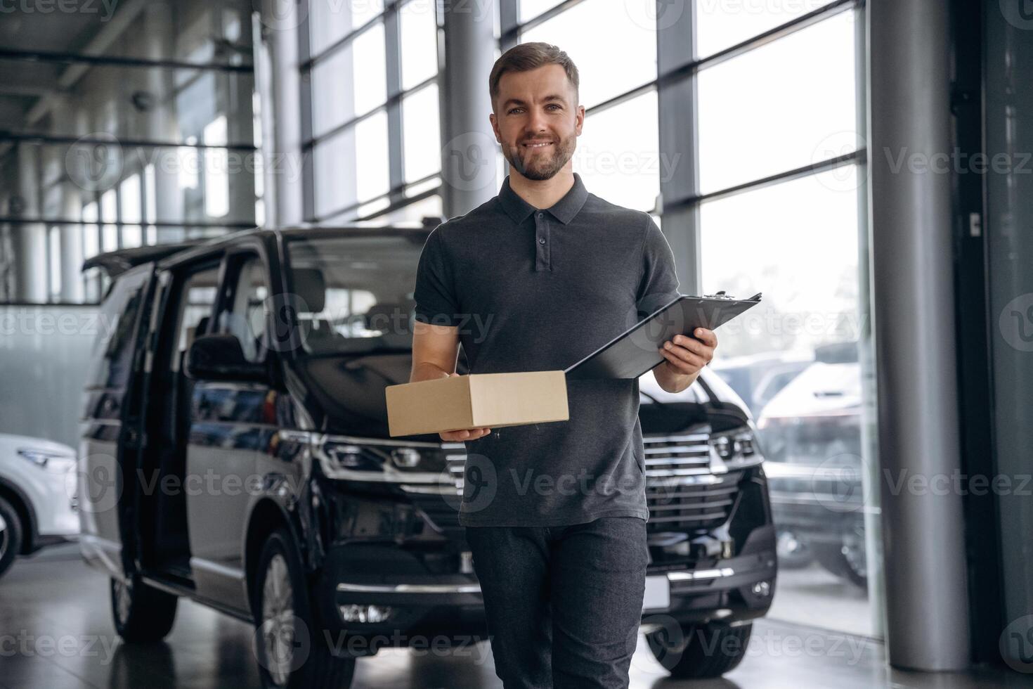 Fast ,delivery service,, standing. Man loader is near the car with a box photo