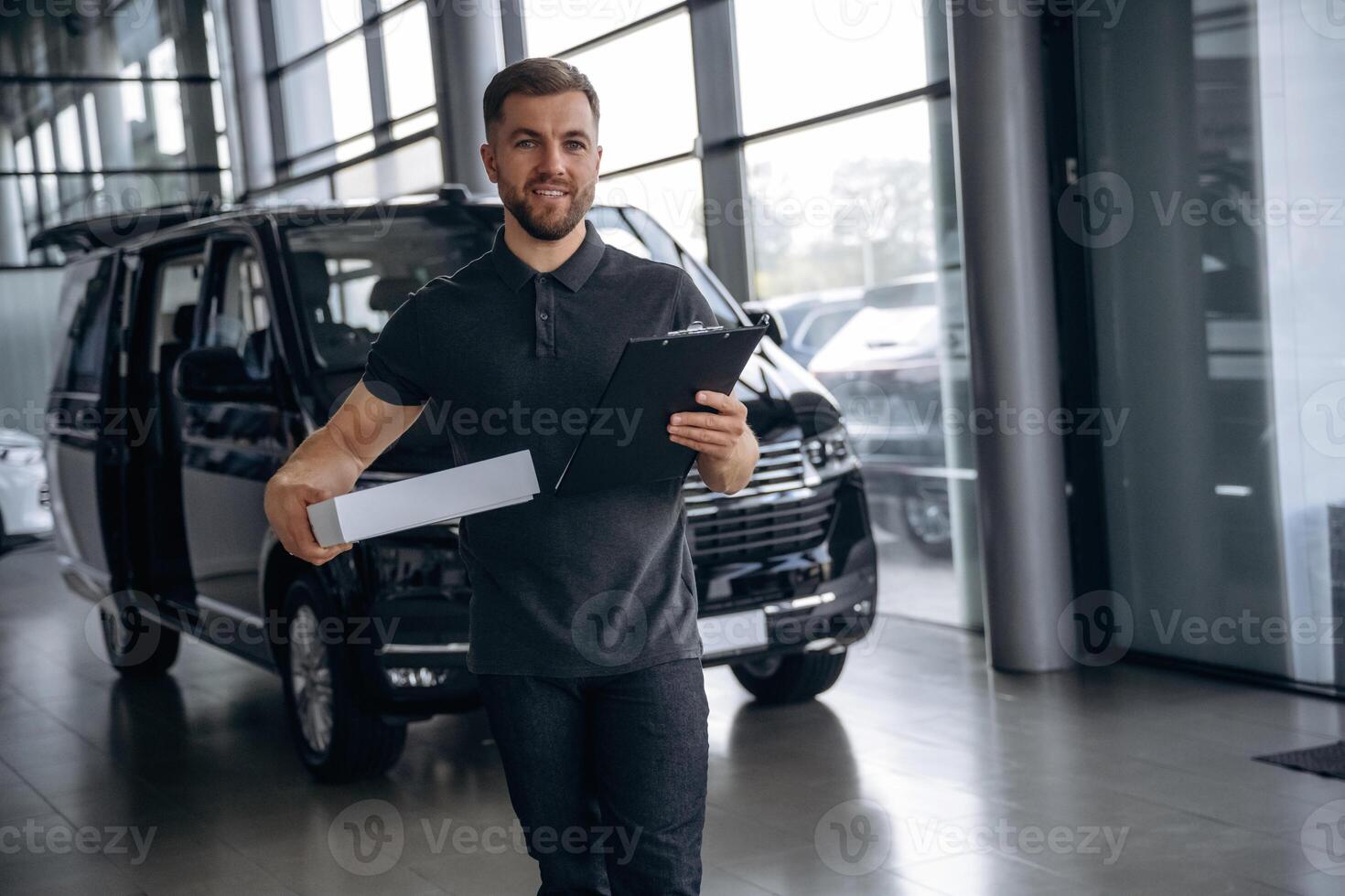 Business of, delivery, with notepad. Man loader is near the car with a box photo