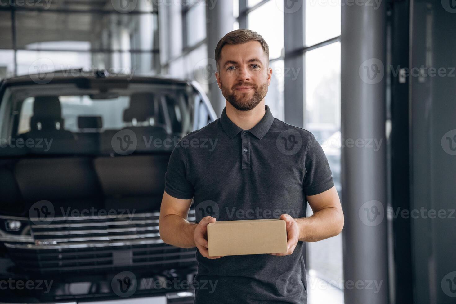 Here's, your delivery. Man loader is near the car with a box photo