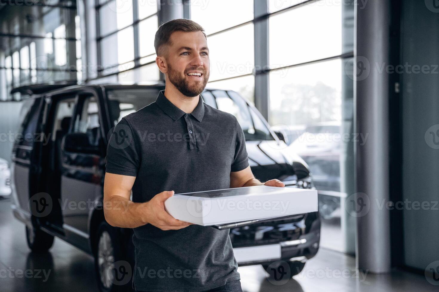 Delivery, man, or loader is near the car with a box photo