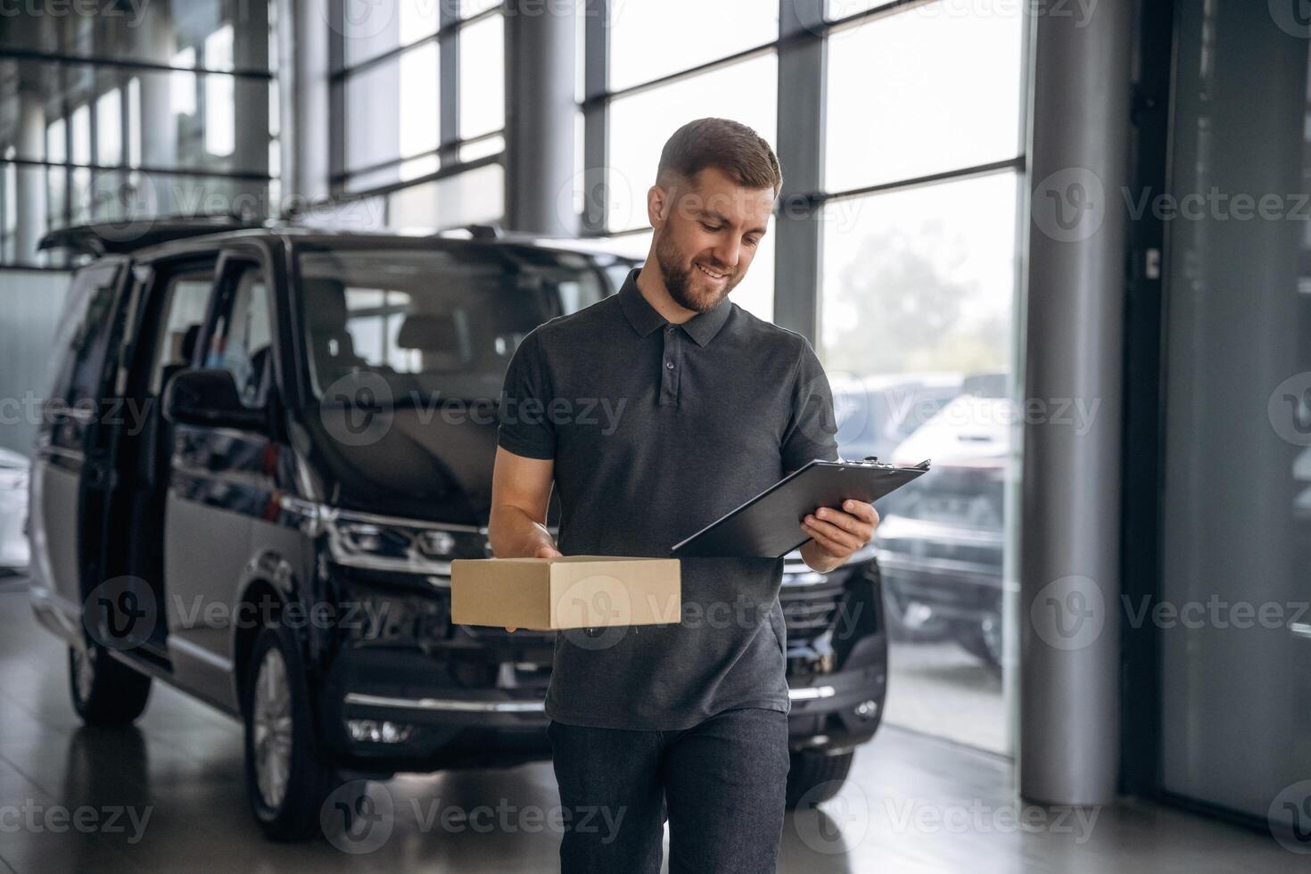 Fast ,delivery service, standing. Man loader is near the car with a box photo