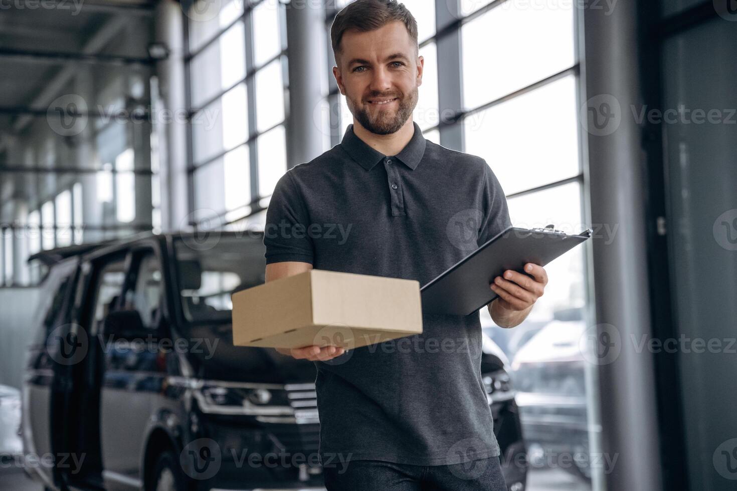 Fast, delivery service, standing. Man loader is near the car with a box photo