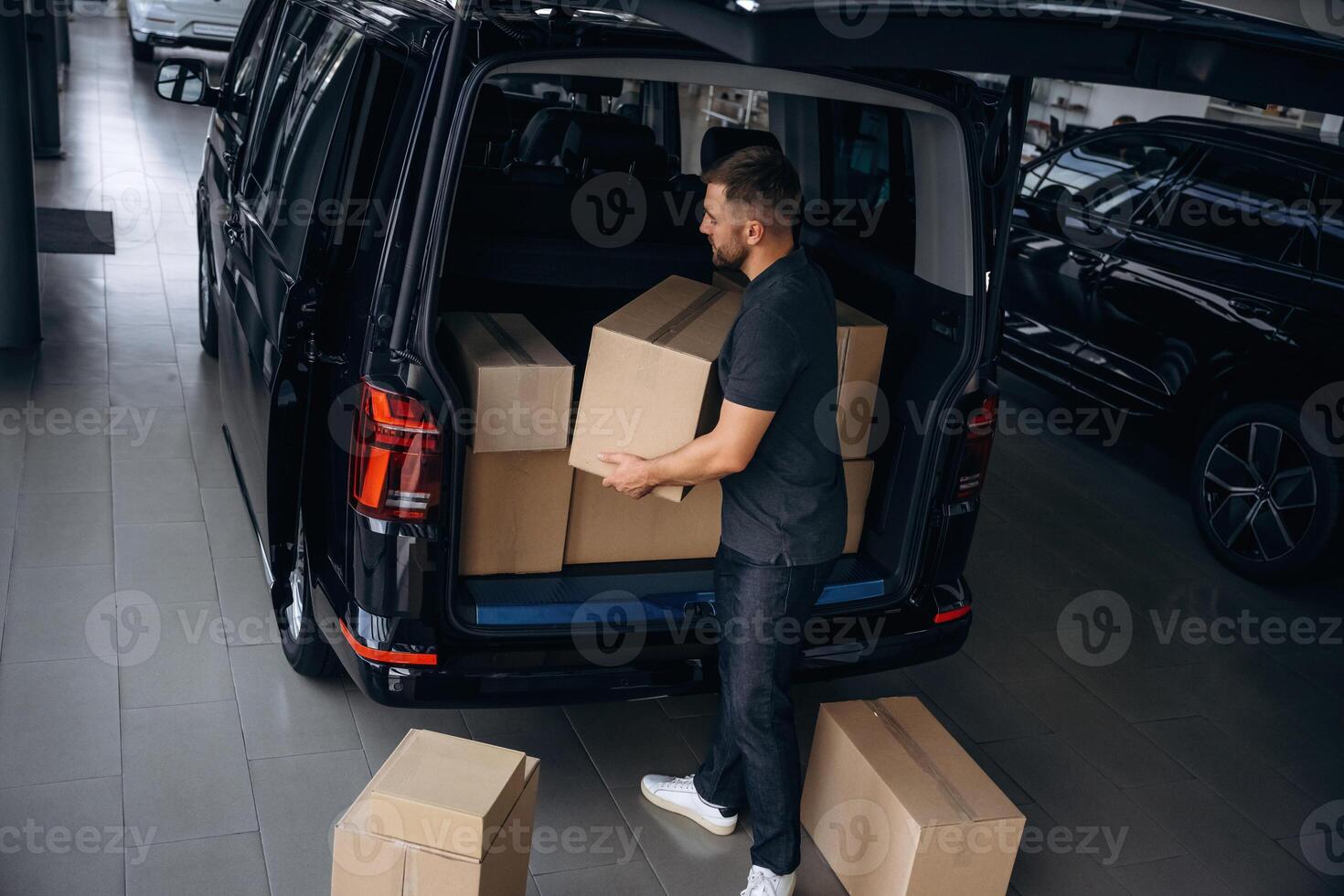 Unloading ,,,the boxes. Delivery man or loader is near the car photo