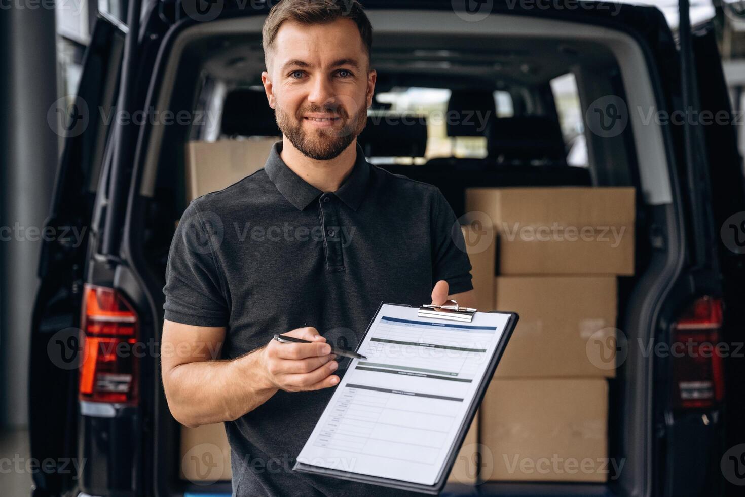Confirm ,the order on notepad. Delivery man or loader is near the car with a box photo
